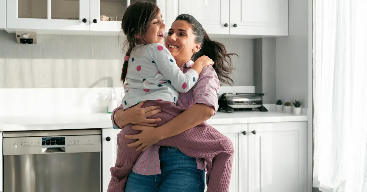 Woman smiling while holding child. Shows the Benefits of Prioritizing Your Mental Health After Baby.
