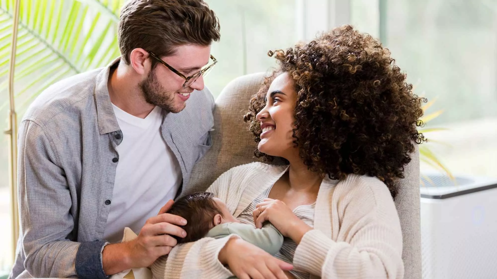 Couple with newborn smiling, illustrating couples counseling for new parents and the strength of their relationship after baby.