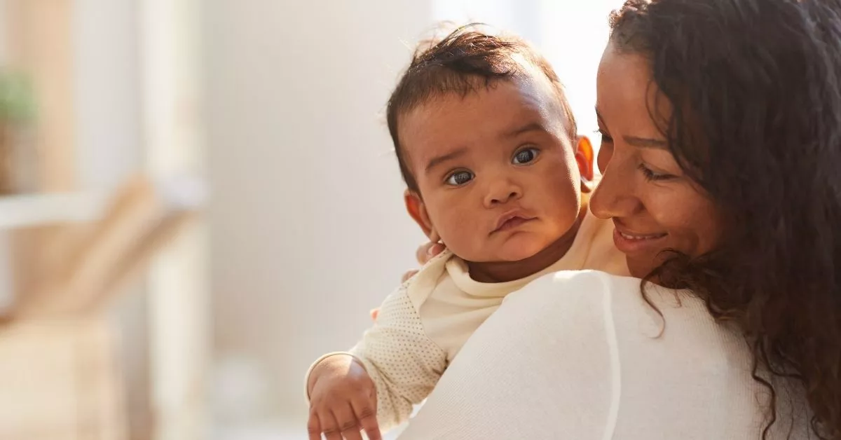 Mother snuggling her baby close, capturing the tenderness of connection as she learns to let go of mom guilt and perfectionism.