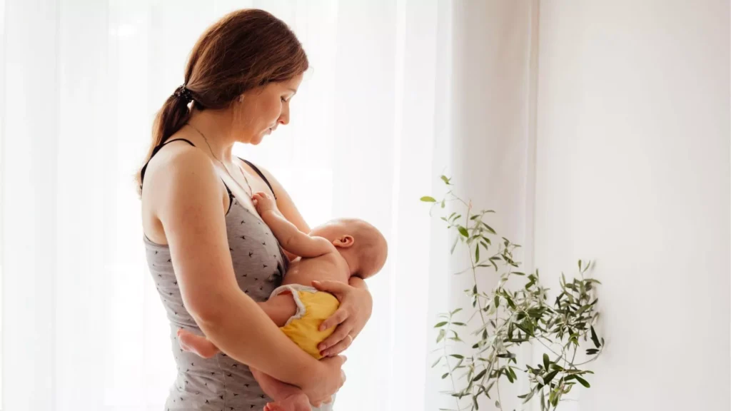 Mother breastfeeding newborn in soft natural light, quiet moment of early motherhood and bonding, although she seems to be thinking that she is not enjoying motherhood.