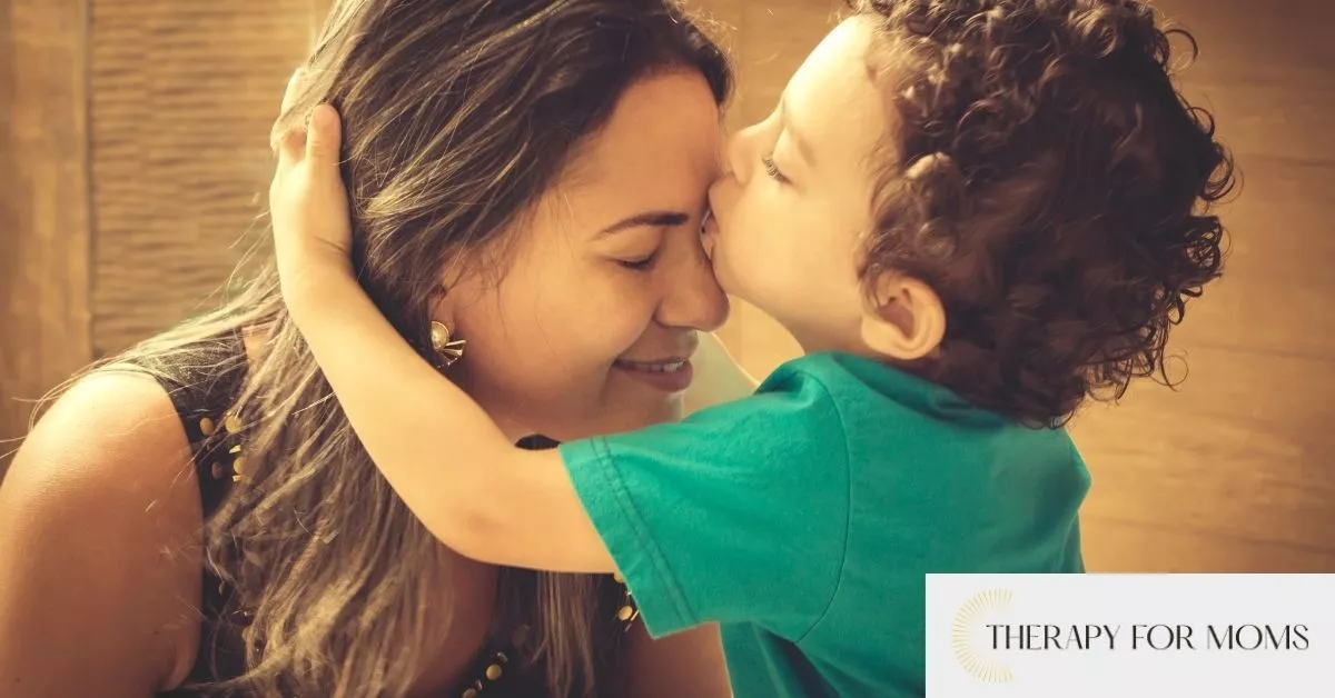 A mother smiles as her young child kisses her forehead, with Therapy for Moms branding in the corner.