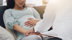 Pregnant woman receiving compassionate support from a therapist during a perinatal counseling session, representing the process of finding specialized mental health care for pregnancy and postpartum challenges in Houston.