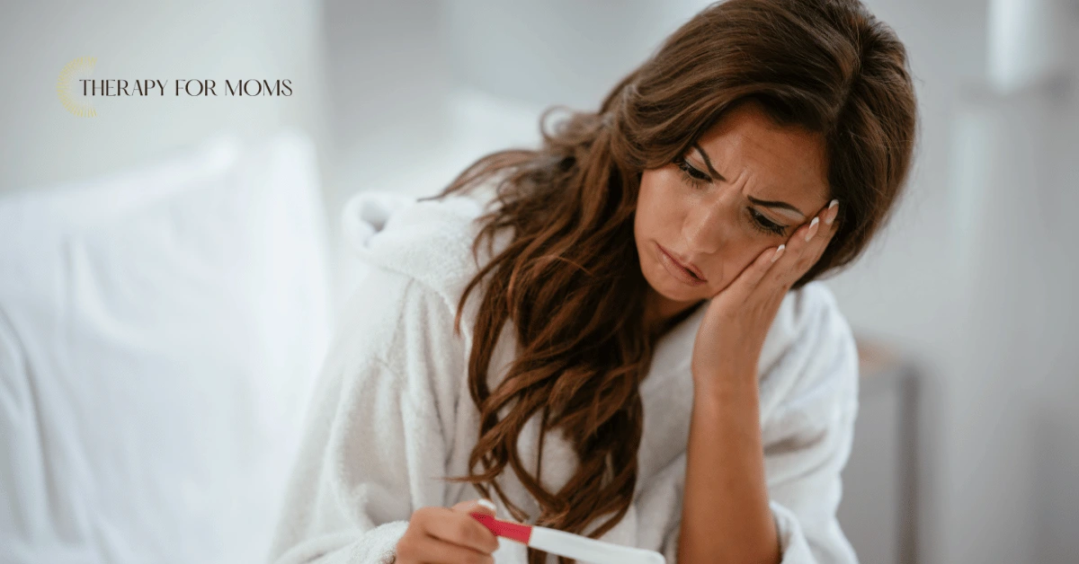 Concerned woman in a bathrobe staring at a pregnancy test with a worried expression, representing tokophobia, the overwhelming fear of pregnancy and childbirth.